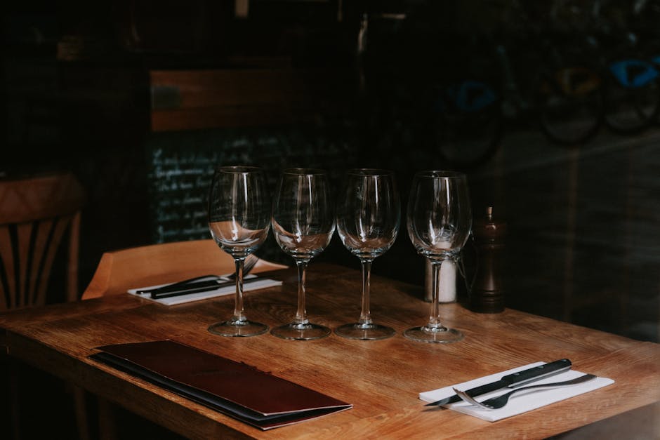 A neatly arranged table with wine glasses and cutlery in a dimly lit restaurant setting